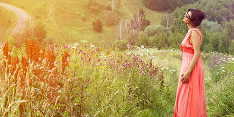 A middle-aged woman in a pink dress in a meadow