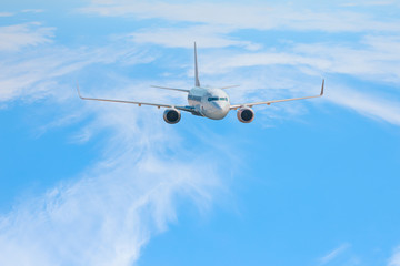 An airplane is flying over low clouds and mountains with blue sky