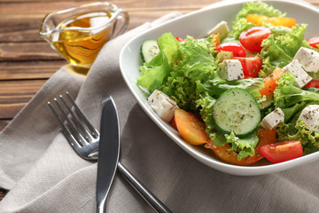 Plate with delicious fresh salad on table