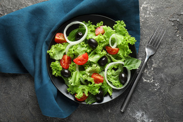 Plate with delicious fresh salad on grey table