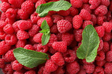 Fresh ripe raspberries with mint leaves as background