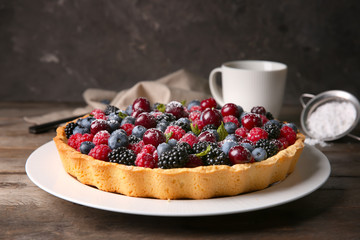 Plate with delicious berry pie on wooden table