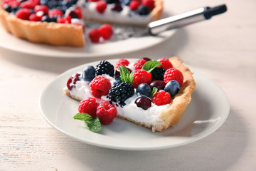 Plate with piece of delicious berry pie on white wooden table