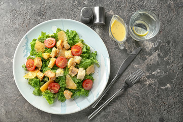 Plate with tasty Caesar salad on table