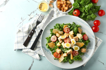 Plate with tasty Caesar salad on table