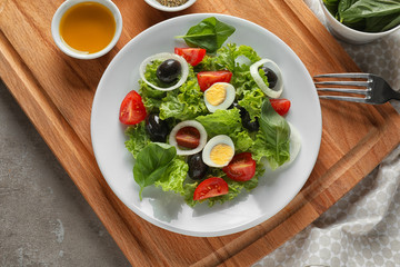 Tasty vegetable salad with boiled eggs and olives on wooden board