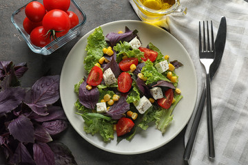 Tasty vegetable salad with feta cheese on grey background