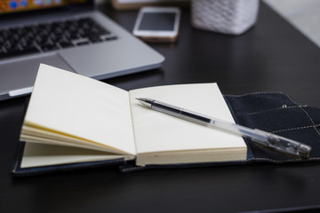 Still life, business, office supplies or education concept : Top view image of open notebook with blank pages and laptope and pen on wooden background, ready for adding or mock up