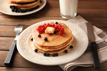 Plate with tasty homemade pancakes and berries on wooden table