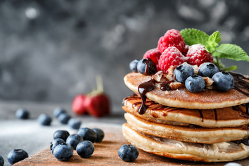 Tasty homemade pancakes with berries on wooden board, closeup