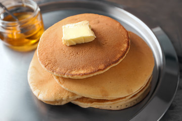 Tasty pancakes with butter and honey on plate