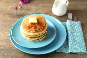 Plate with tasty pancakes on wooden table