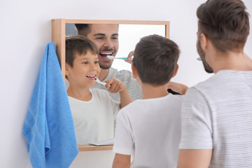 Fototapeta premium Little boy and his father brushing teeth in bathroom