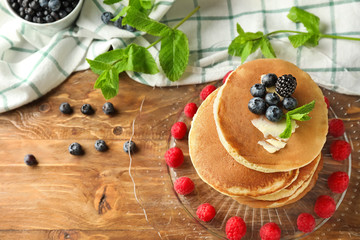 Plate with tasty pancakes and berries on wooden table