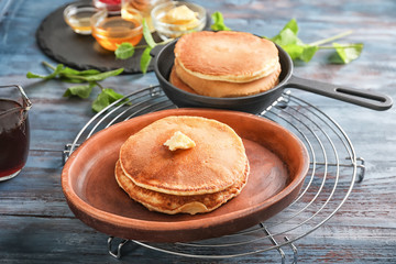Plate and frying pan with tasty pancakes on wooden table