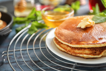 Cooling rack with tasty pancakes on wooden table, closeup