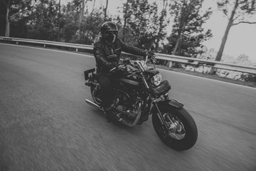 Fototapeta na wymiar Black and white of man riding a classic motorcycle on the road.