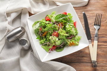 Plate with tasty vegetable salad on wooden table