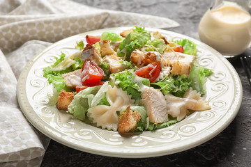 Tasty Caesar salad with pasta on table