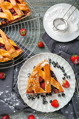 Tasty sliced pie with berries on wooden table