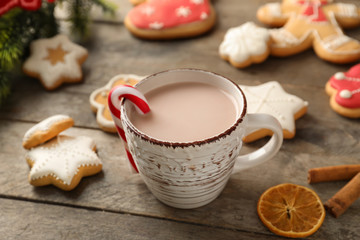 Obraz na płótnie Canvas Cup of hot cocoa with candy cane and cookies on wooden table
