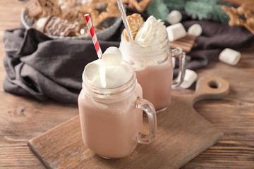 Mason jars of hot cocoa drink on wooden board