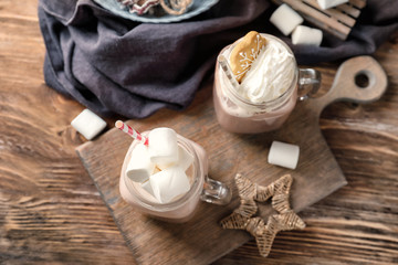 Mason jars of hot cocoa drink on wooden board