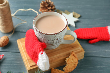 Cup of delicious hot cocoa with knitted mittens on wooden table