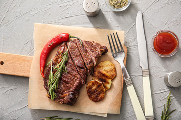 Board with tasty grilled meat, vegetables, spices and herbs on light table