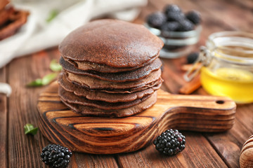 Stack of delicious chocolate pancakes on wooden board