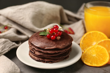 Delicious chocolate pancakes decorated with currant on plate