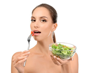 Young woman with fresh vegetable salad on white background