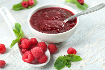 Bowl with tasty raspberry jam on wooden table