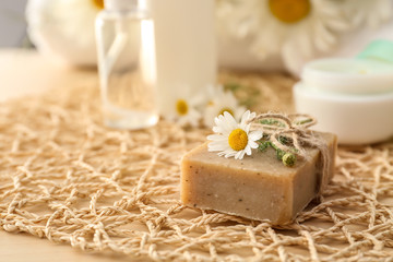 Fototapeta na wymiar Bar of natural soap with chamomile flower on table