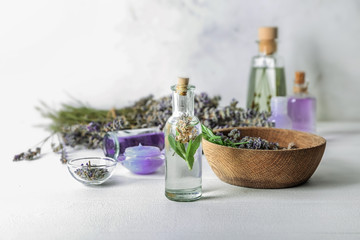 Obraz na płótnie Canvas Bottle of essential oil with lavender on light table