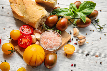 Composition with fresh cherry tomatoes and bread on white wooden background