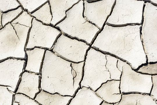 Overhead view of the patterns of a cracked dry grey earth.