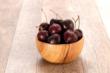 fresh cherry in wood bowl on wooden background 