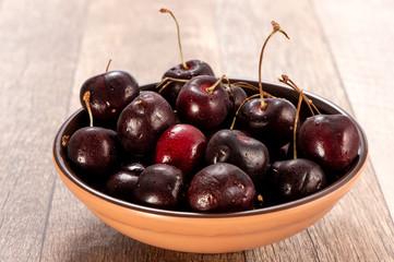 fresh cherry in wood bowl on wooden background 