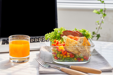 Businesswoman eating organic vegan meals from take away lunch box at  working table with laptop