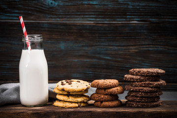 Vintage milk glass with straw and homemade cookies on wooden background