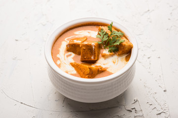 Paneer Butter Masala also known as Panir  makhani or makhanwala. served in a ceramic or terracotta bowl with fresh cream and coriander. Isolated over colourful moody background. selective focus
