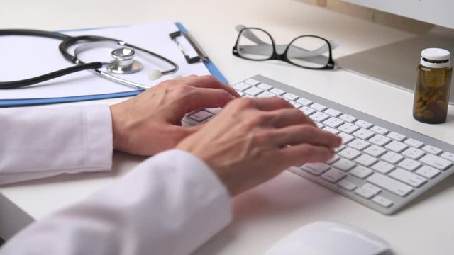 Woman doctor typing medical receipt to patient. Female physician working at computer in clinic. 
