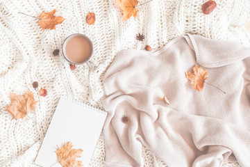 Autumn composition. Cup of coffee, women fashion sweater, dried leaves, plaid, notebook. Autumn, fall concept. Flat lay, top view, copy space