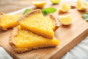 Pieces of tasty lemon pie on wooden board, closeup