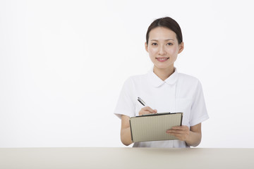 Obraz premium カルテとペンを持って微笑む白衣を着た女性