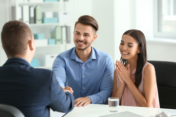 Young man shaking hands with estate agent in office
