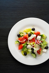 Greece salad White plate with vegetable salades. Tomato and cucumber with olive oil dill onion and parsley olives and cheese feta