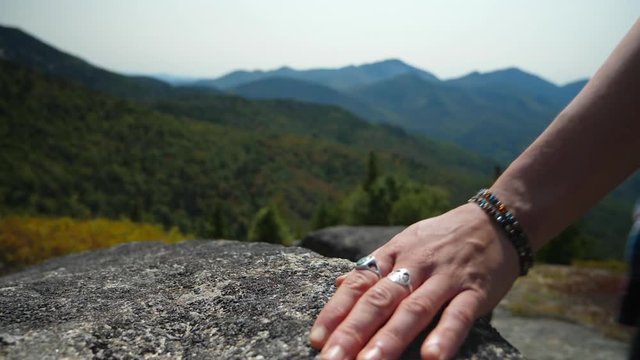 Closeup slow motion of girl's hand running along a rock in the high peaks