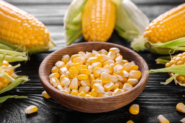 Bowl with corn seeds on wooden table